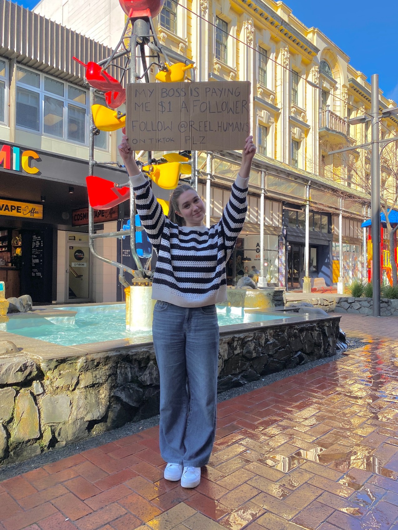 Amelia holding a dollar-a-follower cardboard sign